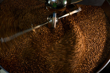 Roasting coffee beans in a large industrial roaster in a bustling café