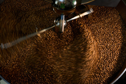 Roasting coffee beans in a large industrial roaster in a bustling caf&eacute;