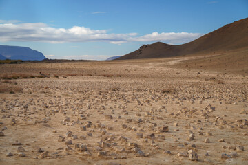 Geothermal terrain with steaming vents, golden-orange soil, and rocky formations near Námafjall, Iceland.