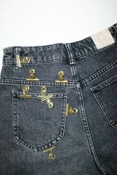 Close-up of jeans with colourful office supply paper clips on a pocket