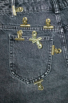 Close-up of jeans with colourful office supply paper clips on a pocket