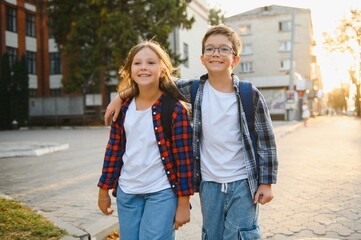 Happy schoolchildren near the school. A boy and a girl are primary school students. School friendship