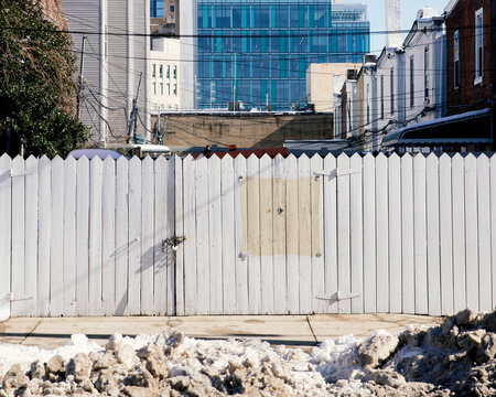 Street in West Philadelphia with fence, row homes, and buildings