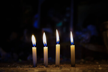 Four Lit Candles Burning Brightly in Deep Darkness