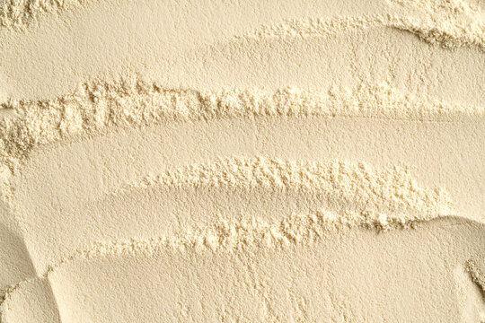 Whey protein powder as textured background, top view
