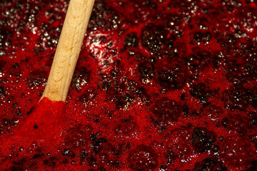 close up of blackberry jam boiling with wooden spoon.