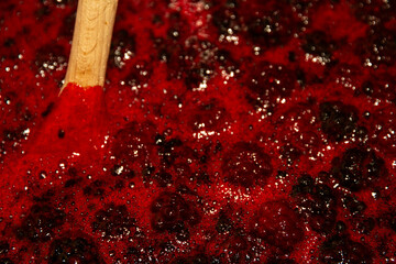 close up of blackberry jam boiling with wooden spoon.