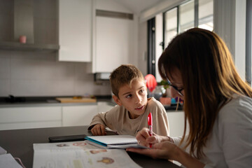 Mother Helping Child with Homework at Kitchen Table