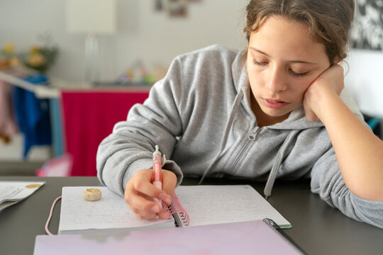 Student Writing in Notebook at Home