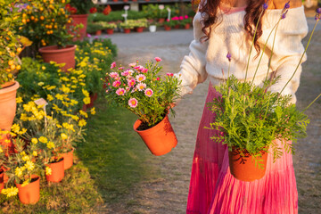 A woman selecting flowers among various potted plants