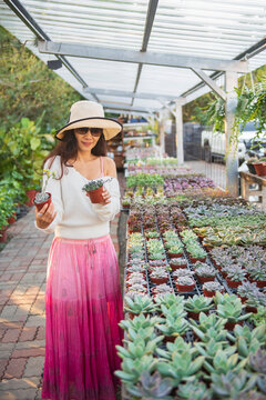 A woman selecting succulent plants in a greenhouse