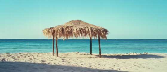 Cool shade of a beach cabana surrounded by ocean and sand on a sunny day