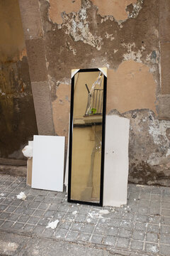 Broken mirror and other furniture items on street with reflection