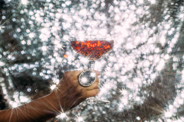 Holding red champagne glass on shiny background. Festive, celebration.