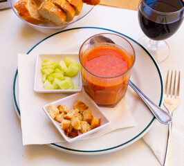 Traditional Spanish refreshing pureed soup Gazpacho from tomatoes served in glass with toasted bread and chopped cucumbers