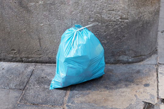 Bright blue plastic bag in a corner of concrete wall urban city 