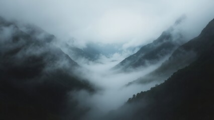 Obraz premium Misty mountain valleys under cloudy skies create a mystical atmosphere at dawn