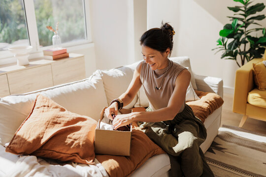 Happy woman opening parcel in bright living room