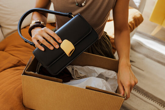 Woman unpacking handbag from cardboard box at home
