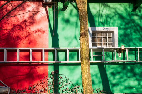 Vibrant Red Green Building Wall with Tree Shadows and Metal Deta
