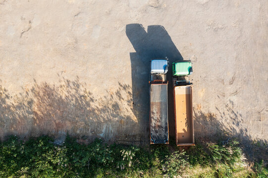 Aerial View Two Dump Trucks Against Wall With Dramatic Shadows