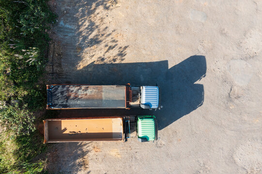 Aerial View Two Dump Trucks Against Wall With Dramatic Shadows