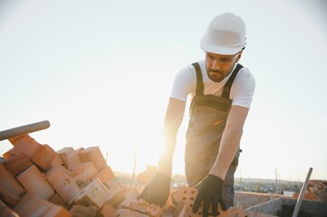 Man bricklayer installing bricks on construction site