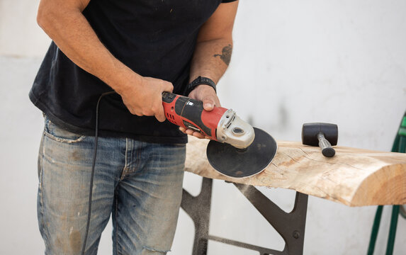 A carpenter using a rotary sander