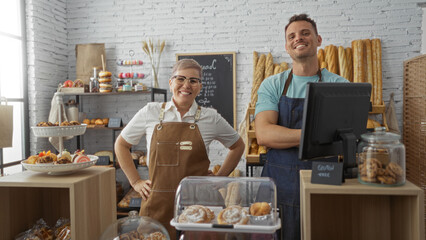 Two adult bakers, a woman and a man, standing confidently in their indoor bakery shop, surrounded by freshly baked pastries and bread on display.