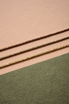 Gold chains aligned parallel on beige and green background
