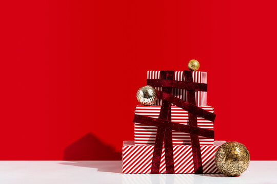 Pile of gift boxes and shiny ornaments wrapped with red velvet ribbon