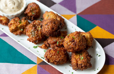 Bite-Sized Fried Eggplant Fritters Finger Food Appetizer with Dipping Sauce on a colorful geometric background