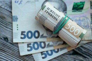Many five hundred hryvnia money bills lies on wooden background. Ukrainian national currency close...