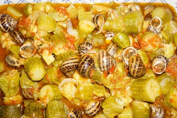 Traditional Cretan food, snails with zucchini in tomato sauce baked in a pot with tomato sauce served on a vintage plate
