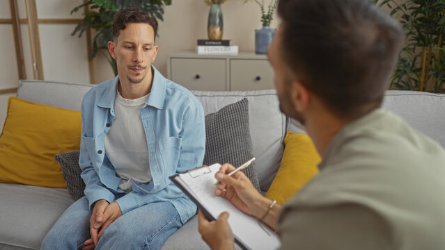Man in therapy session at home while therapist takes notes in a cozy living room setting