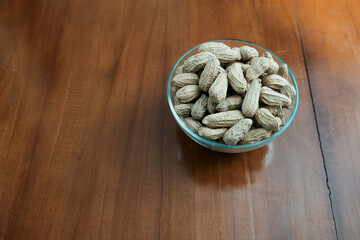 Organic Raw Peanuts in a glass Bowl on the wooden table, healthy snack