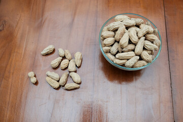 Organic Raw Peanuts in a glass Bowl on the wooden table, healthy snack
