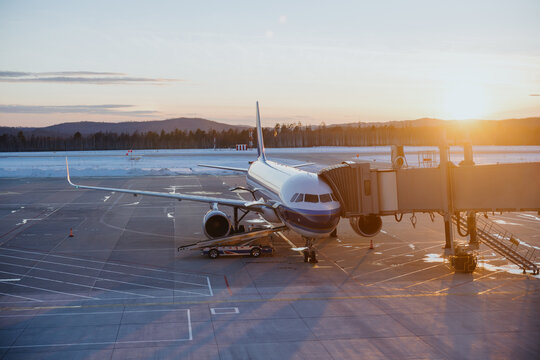Airplane Docked at Airport Gate During Sunset - Powered by Adobe