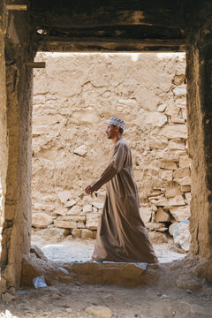 Omani man walking through ancient doorway in traditional clothing