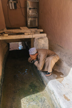 Muslim man performing wudu ablution ritual in small water basin