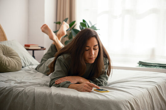 Relaxed woman using mobile phone in bed