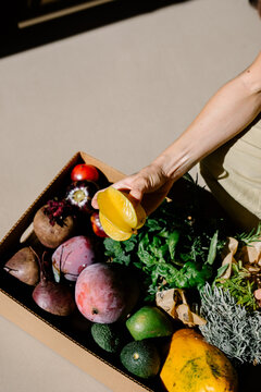 Anonymous hand taking a carambola from a box of home-grown fruits