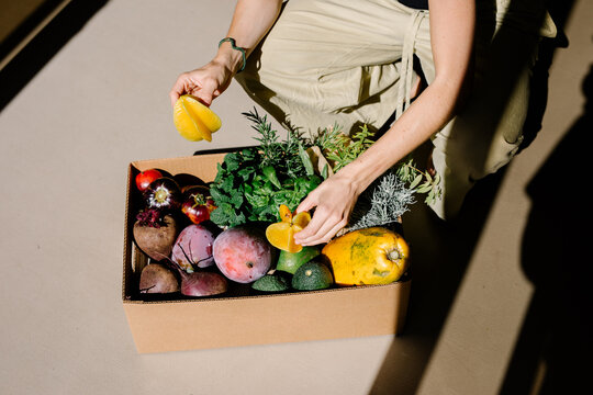 Unknown lady picking a carambola from a box filled with organic fruits
