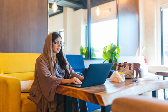 Young emirati businesswoman working on laptop in modern cafe