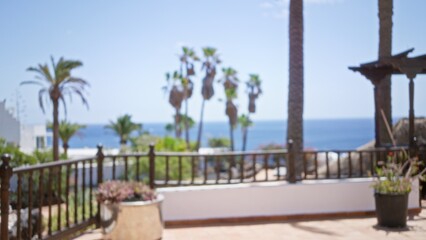 Blurred outdoor background of lanzarote, canary islands with defocused palm trees and ocean view on a sunny day.