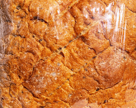 Close-up of crusty bread under transparent plastic wrap