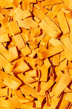 Closeup macro view of raw orange tagliatelle noodle strips