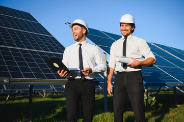 Solar panel farm. Two European engineers inspect solar panels. Workers at a solar panel farm