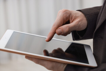 Businessman using tablet indoors, closeup. Modern technology
