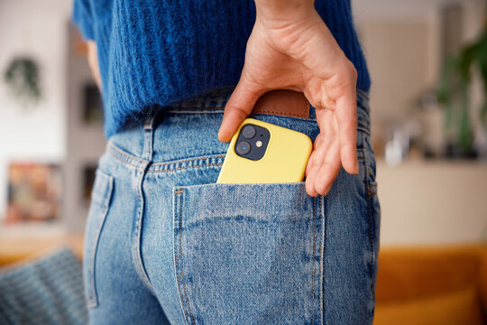 Anonymous woman putting smartphone into back pocket of jeans